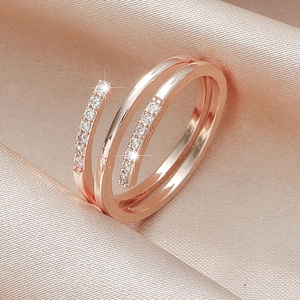 Double-layered rose gold ring with pavé crystals on pink satin background