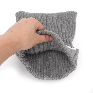 Détail de la grande élasticité et de l'épaisseur du bonnet gris en maille avec oreilles de chat
