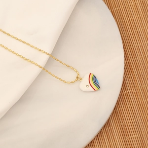Detail of gold bead chain with rainbow heart pendant on white marble and bamboo background