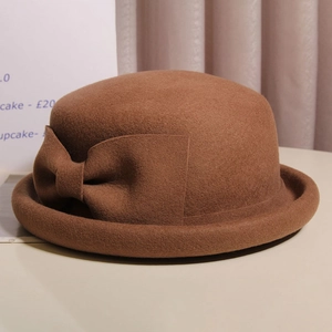 Detail of a brown wool felt cloche hat featuring a curled brim and a side bow knot