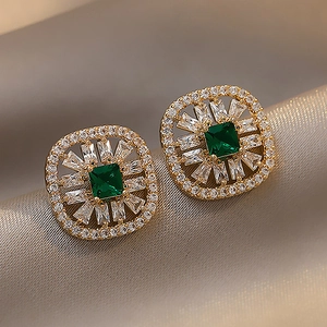 Macro shot of vintage gold earrings with square emerald stones and sparkling crystals
