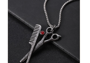 Close-up of vintage scissors and comb pendant with a red rhinestone on a box chain