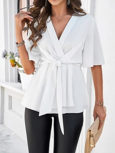 Détail du chemisier blanc élégant à col en V avec ceinture nouée et manches mi-longues