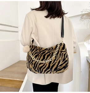 Detail of tiger print faux fur tote bag with gold chain and plush ball charm accessory