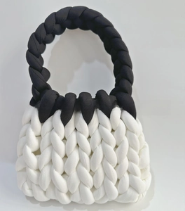 Macro detail of chunky hand-knit bag featuring black and white yarn weaving texture
