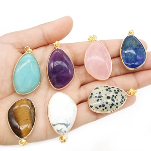 Natural crystal agate teardrop pendants with gold plated edges held in hand