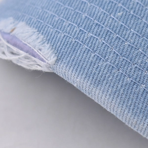 Macro detail of distressed denim baseball cap brim with white stitching and purple lining