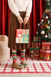 Festive combed cotton Christmas socks and gift bag displayed by a decorated tree