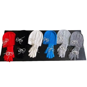 Knitted hat and gloves set with white bow accents in six vibrant colors on wood background