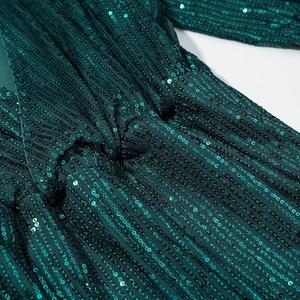 Macro shot of dark green sequin texture and gathered waist detail on women's dress