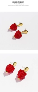 Detailed view of red glass raspberry earrings with gold hammered metal stud accents