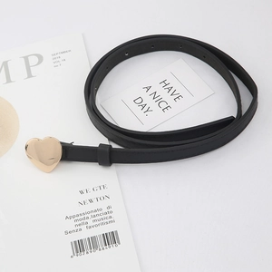 Women's thin black belt with a gold heart buckle shown with stylish lifestyle props