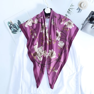 Detailed macro view of deep purple satin scarf featuring white magnolia floral patterns