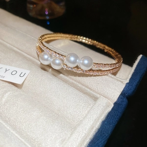 Détail macro du bracelet double couche avec perles blanches et pavé de strass étincelants