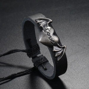 Macro shot of black leather bracelet with metal winged heart charm and Love engraving