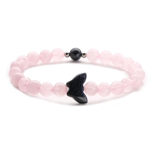 Detail of pink crystal beaded bracelet featuring a dark blue fishtail pendant and metal spacers