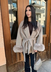 Detail of elegant beige wool coat featuring luxurious faux fur trim on the sleeves