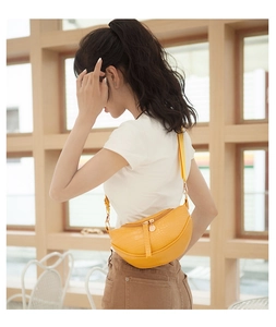 Detail of yellow crocodile-patterned half-moon crossbody bag with gold metal zipper and strap