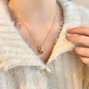 Detailed close-up of 18k gold-plated fortune bag pendant with pearls and red beads