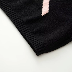 Close-up of black ribbed knit sweater cuff with pink floral jacquard pattern detail