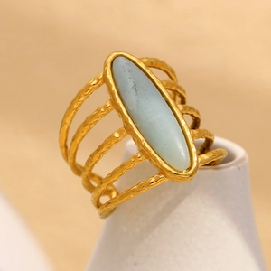 Macro detail of wide hammered 18K gold plated ring with oval light blue stone