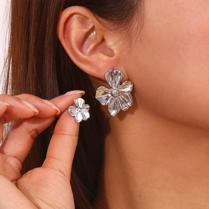 Macro shot of silver flower earrings with crystal center worn on model ear