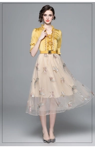 Close-up of yellow ruffled silk blouse with embroidered mesh skirt and waist belt