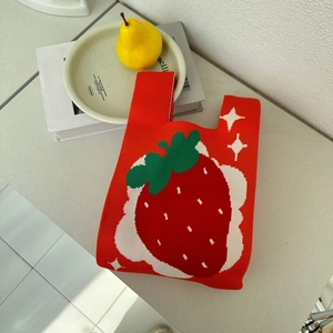 Detail shot of a handmade red knit tote bag featuring a vibrant strawberry pattern texture