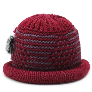 Detailed close-up of thickened knitted winter hat with floral accent and rolled brim
