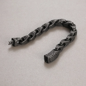 Macro detail of hammered texture and vintage oxidized finish on men's steel chain bracelet