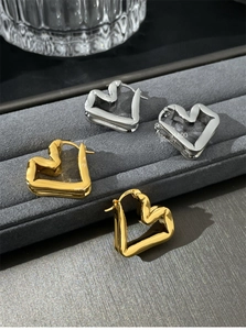 Macro shot showing S925 hallmarks on gold and silver heart-shaped hoop earrings