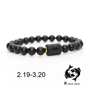 Detail of matte black beads bracelet with golden spacers and Pisces zodiac symbol