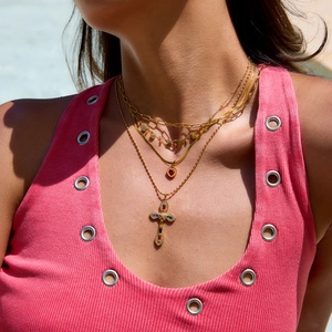 Close-up of layered 18K gold stainless steel necklaces with heart and cross pendants