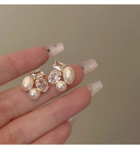 Macro shot of gold geometric earrings with baroque pearls and faceted cubic zirconia stones