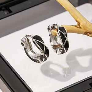Vue détaillée des créoles en argent avec motif de grille en émail noir sur bois