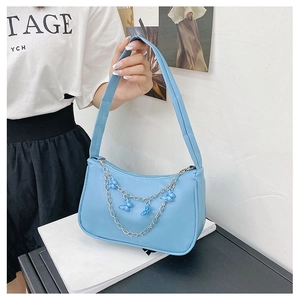 Close-up of light blue leather underarm bag featuring a silver butterfly chain strap detail