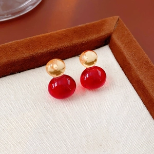 Macro shot of amber and red resin double sphere stud earrings in a jewelry box