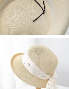 Détail du chapeau de paille avec ruban à pois blancs et plaque métallique de logo chic