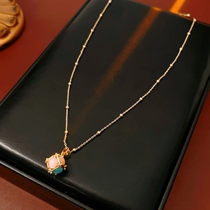 Detail of gold plated necklace featuring colorful opal cube charms on a black leather cushion