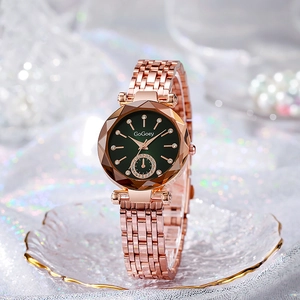 Detail of rose gold watch with deep green dial and crystal markers on glass tray