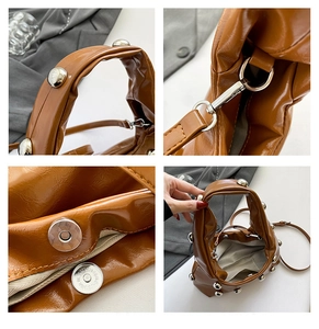 Detail of brown glossy leather bag featuring silver round rivets and magnetic closure