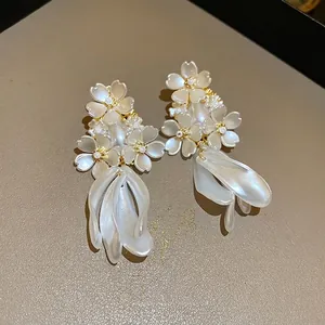 Boucles d'oreilles florales élégantes avec perles et métal doré sur présentoir en cuir