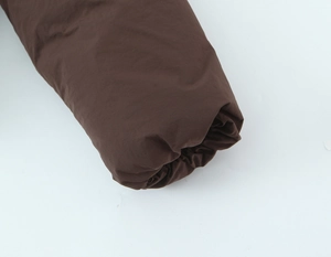 Detail of elastic cuff on dark brown puffer jacket showing high-quality fabric texture