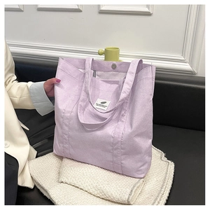 Detail of lavender corduroy tote bag with magnetic button closure and white patch