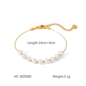 Detailed view of a gold thin chain bracelet with white pearls and small gold beads