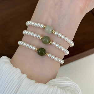 Three-piece pearl bracelet set with green nephrite jade beads on elegant female wrist