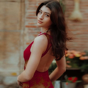 Detail showing the intricate red lace pattern and backless design of the evening dress