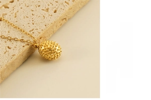 Close-up of 18k gold plated stainless steel durian pendant necklace on stone background