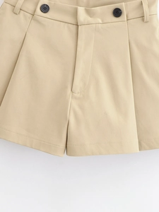 Détail d'un short en coton beige avec passants de ceinture et boutons noirs contrastés