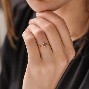 Detailed shot of an 18k gold ring featuring an oval purple zircon and side crystals